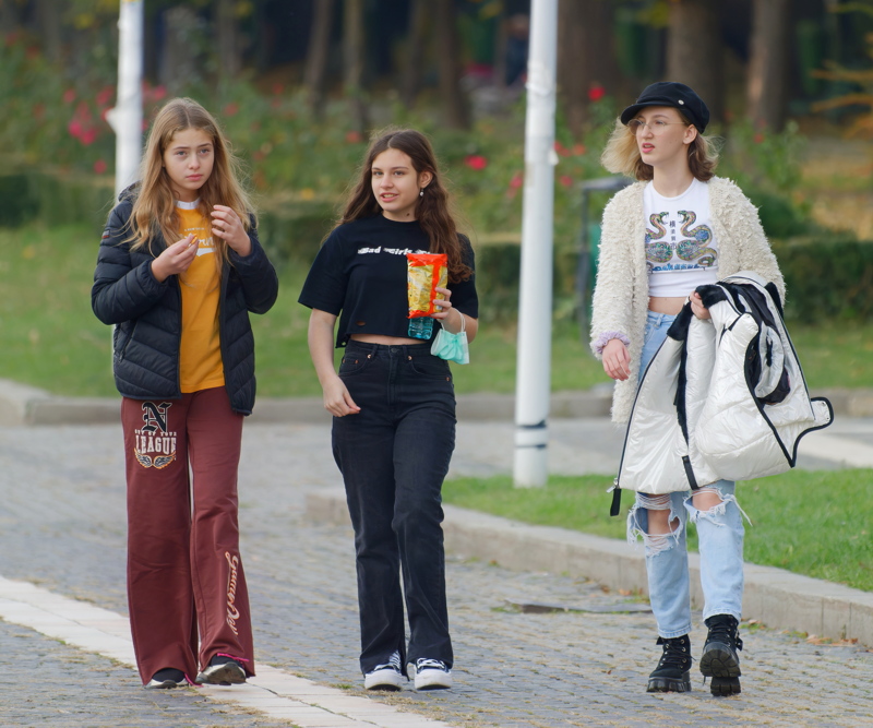 14 - Three young people walking together on a paved path in a park